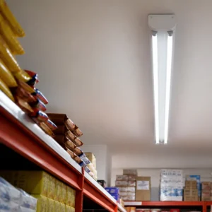 Two European T8 LED glass tubes installed in a ceiling fixture in an indoor stockroom