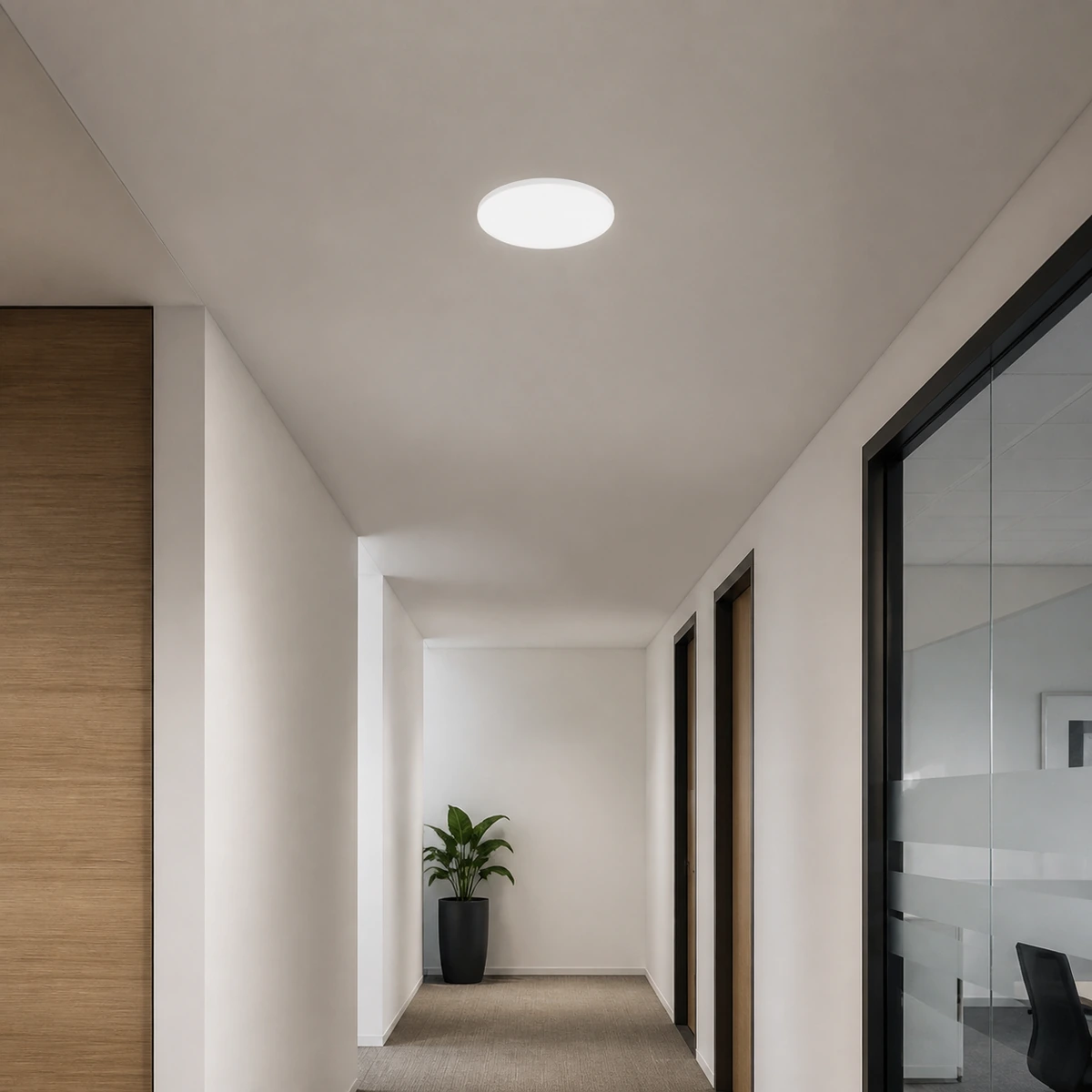 Round frameless recessed LED panel installed in an office corridor ceiling