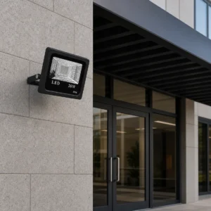 Unlit black RGB LED flood light mounted by its bracket at a covered commercial entrance