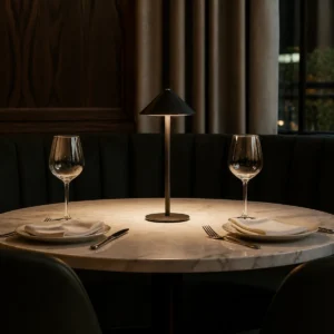Black tall cone-shade cordless LED table lamp on a restaurant dining table