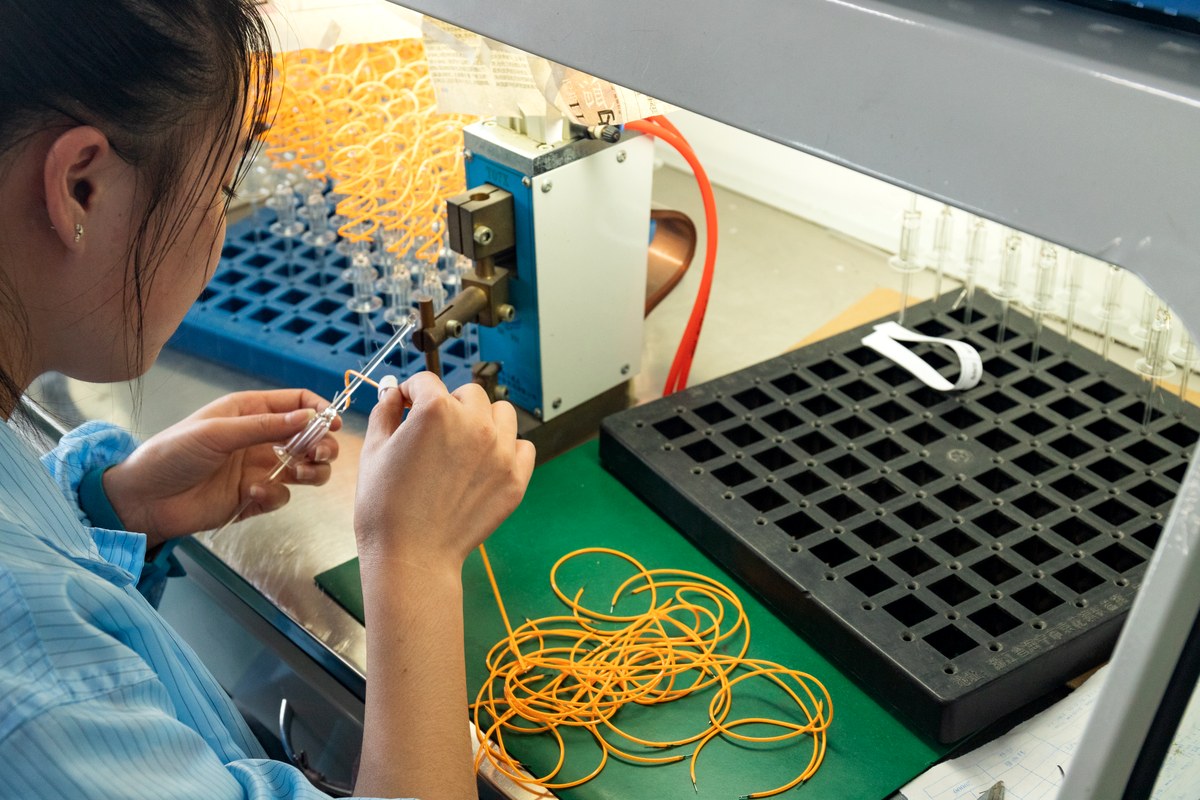 New Lights production operator assembling an LED filament lamp